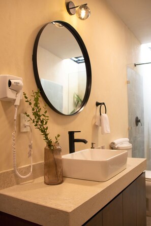 A bathroom with a large oval mirror, a white sink, a hairdryer, and a towel rack. -  Casa Jarana, Paseo de Montejo by Cercana (Mérida)