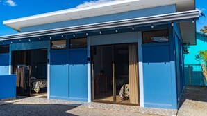 A modern building with a flat roof, large sliding glass doors, and a covered outdoor area. - Cabinas Arenal Home (La Fortuna)