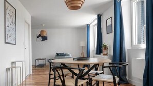 Un espace repas moderne avec un plancher en bois, une table ronde et des chaises noires.