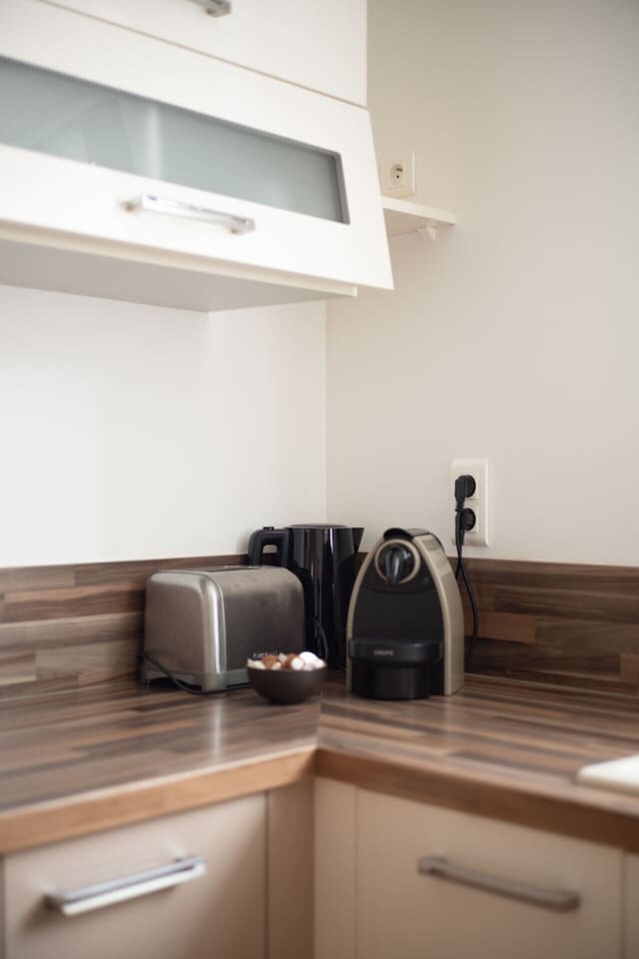 A kitchen with a toaster, a coffee maker, and a bowl of eggs on the counter.