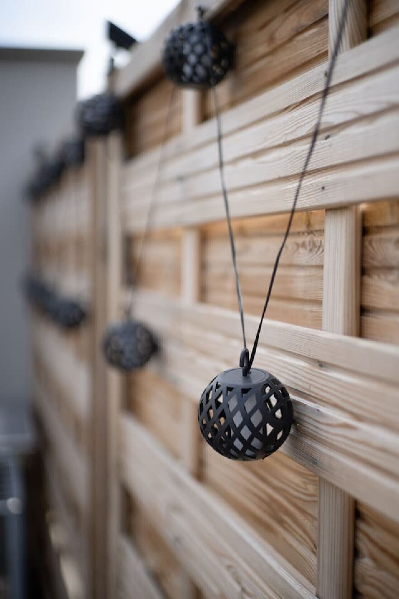 Una cerca de madera adornada con esferas decorativas colgantes.