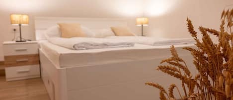 Una cama bien hecha con sábanas blancas y dos lámparas de noche.