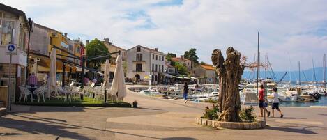 Un puerto deportivo con barcos, un árbol central y zonas de estar al aire libre.