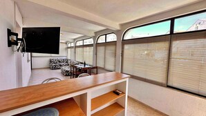 A compact living space with a wooden desk, a sofa, and a TV mounted on the wall. - Holiday apartment with balcony and sea view (Crikvenica)