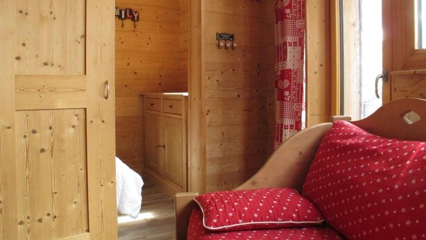 A wooden room with a bed, a small cabinet, and a door leading to another room. - 10m from ski slopes, 3rd floor, balcony, tv, ski locker, 28m², Avoriaz (Avoriaz)