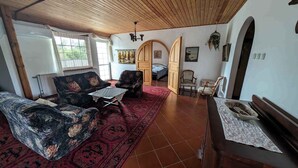 A cozy room with a wooden ceiling, a red patterned rug, and a bed with a blue bedspread. - Holiday apartment with large garden, Wi-Fi and air conditioning (Kehidakustány)
