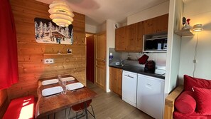 A compact kitchen with wooden cabinets, a Bosch dishwasher, and a dining area with a wooden table and chairs.