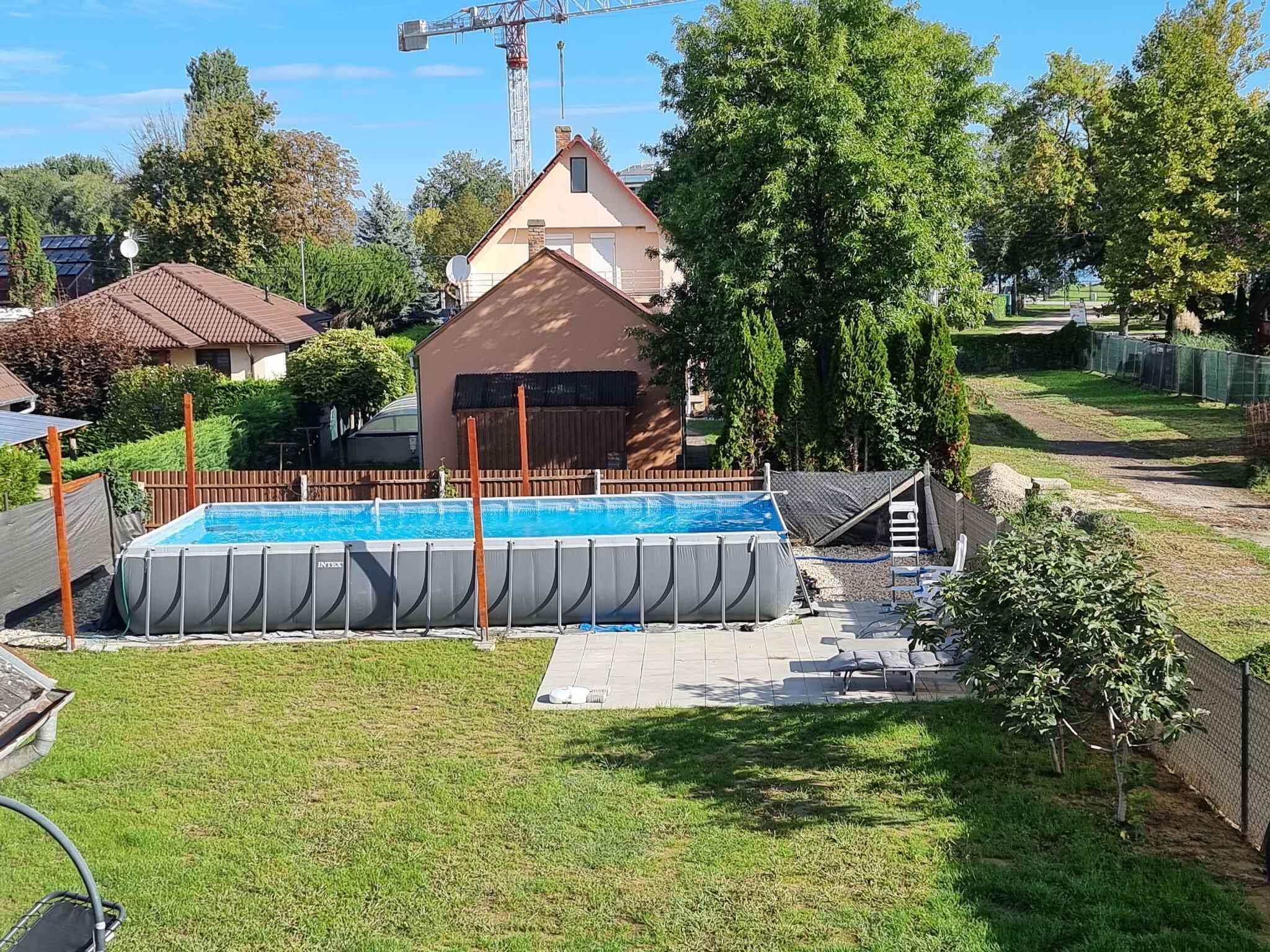 A residential area with a swimming pool, a house, and a fenced yard.