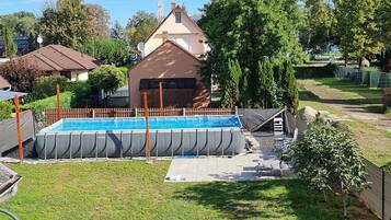 A residential area with a swimming pool, a house, and a fenced yard.