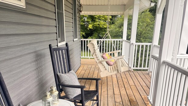 A wooden deck with two rocking chairs and a table, a hanging swing, and a lantern. - Peaceful Pines Hideaway  (Nottingham)