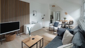Een moderne woonkamer met een bank, een salontafel, een televisie en een keuken op de achtergrond.