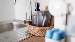 A kitchen sink with a faucet, a bottle of hand soap, a toothbrush, and a cup with blue objects. - // Bismarck 1884 - B6 // (Norderney)