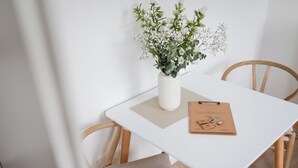 A white table with a clipboard and a white vase with flowers.