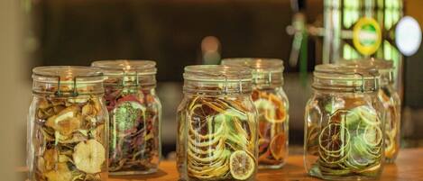 Cinq bocaux en verre contenant des fruits et des légumes séchés, posés sur une surface en bois.