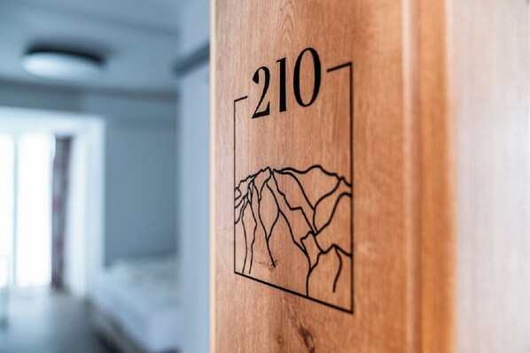 A wooden door with the number 210 and a mountain landscape etched into it. - Aktivhotel Pehab (Ramsau am Dachstein)