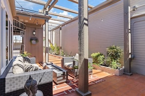 A covered patio area with a seating arrangement, a fire feature, and potted plants.