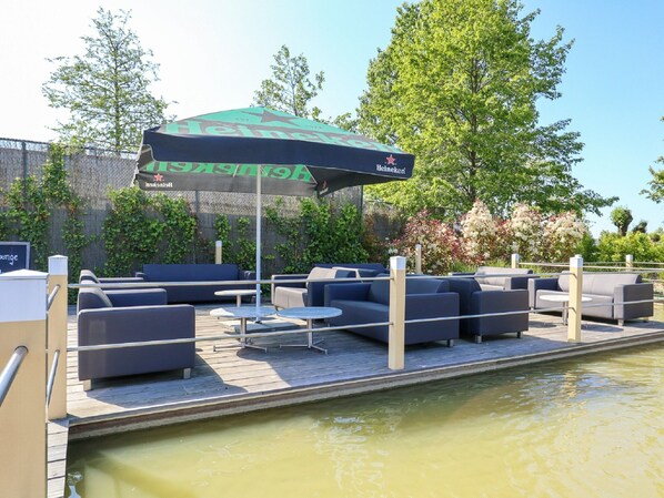 Un espace extérieur aménagé avec des sièges, un parasol à l’effigie de la marque Heineken, des canapés et une petite table.