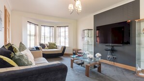 A modern living room with a sofa, coffee table, and a flat-screen TV mounted on the wall.