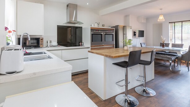 A modern kitchen with a central island, stainless steel appliances, and a dining area with bar stools.