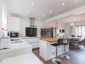 Una cucina moderna con isola centrale, elettrodomestici in acciaio inossidabile e zona pranzo con sgabelli da bar.