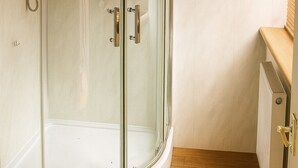 A modern bathroom with a glass shower enclosure, a toilet, and a radiator. - Vintage Studio near NEC & BHX (Birmingham)