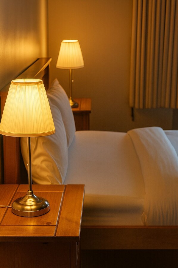 Ein Hotelzimmer mit einem Bett, zwei Nachttischlampen und einem Holznachttisch.