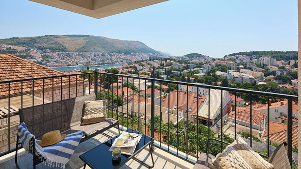 A balcony with a view of a cityscape, including buildings and a hill.