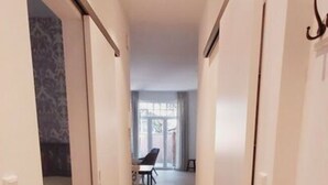 A narrow hallway with wooden flooring leading to a dining area with a table and chairs. - Holiday Apartment Kapteins Kamers (Borkum)