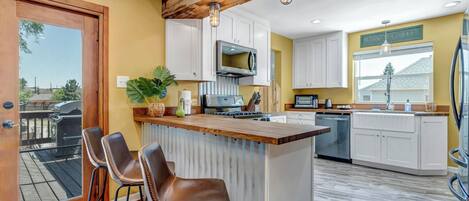 A kitchen with a wooden ceiling, white cabinets, and a central island with bar stools.