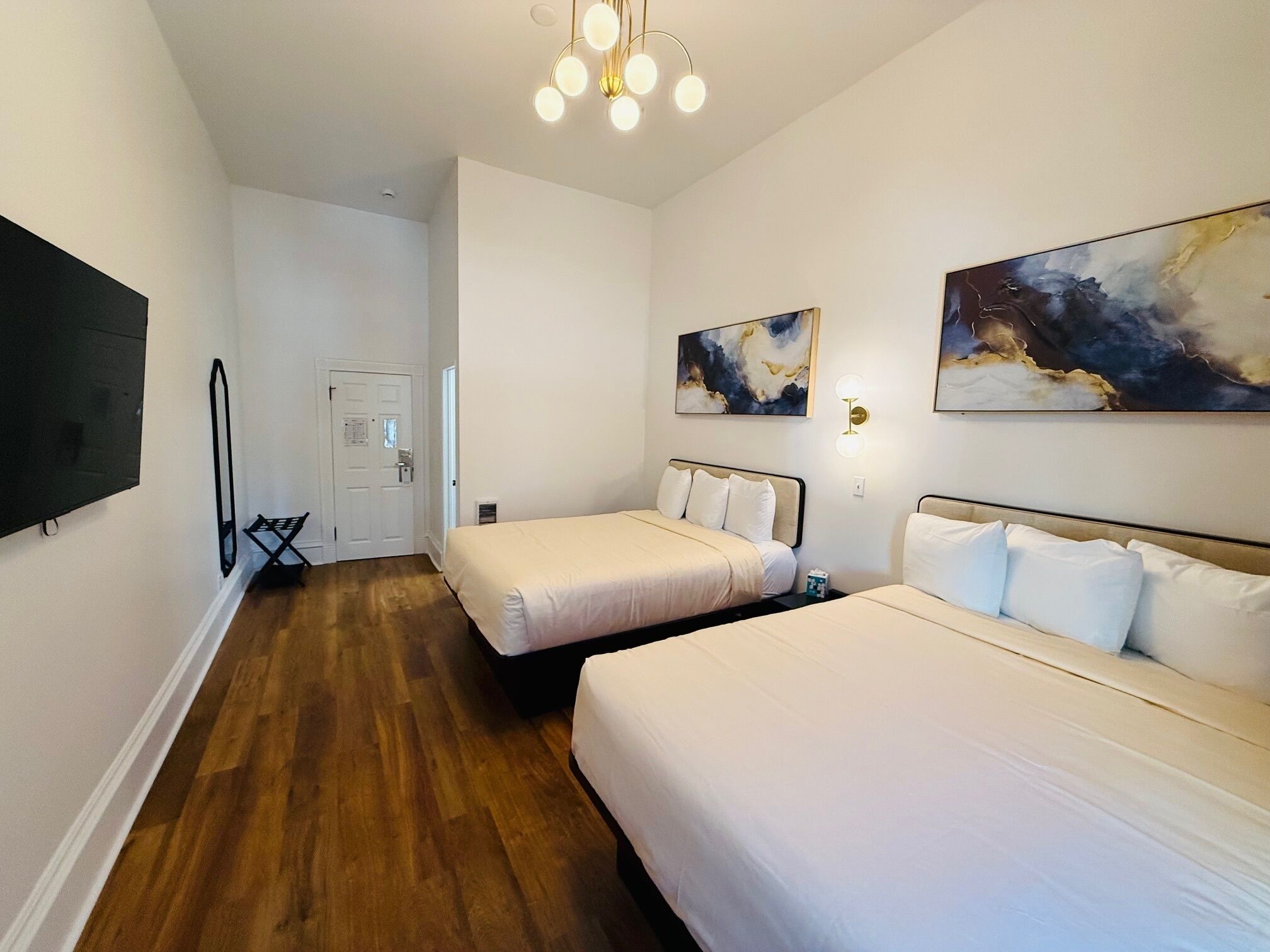 Ett hotellrum med två sängar, en platt-TV, konstverk på väggarna och ett trägolv.
