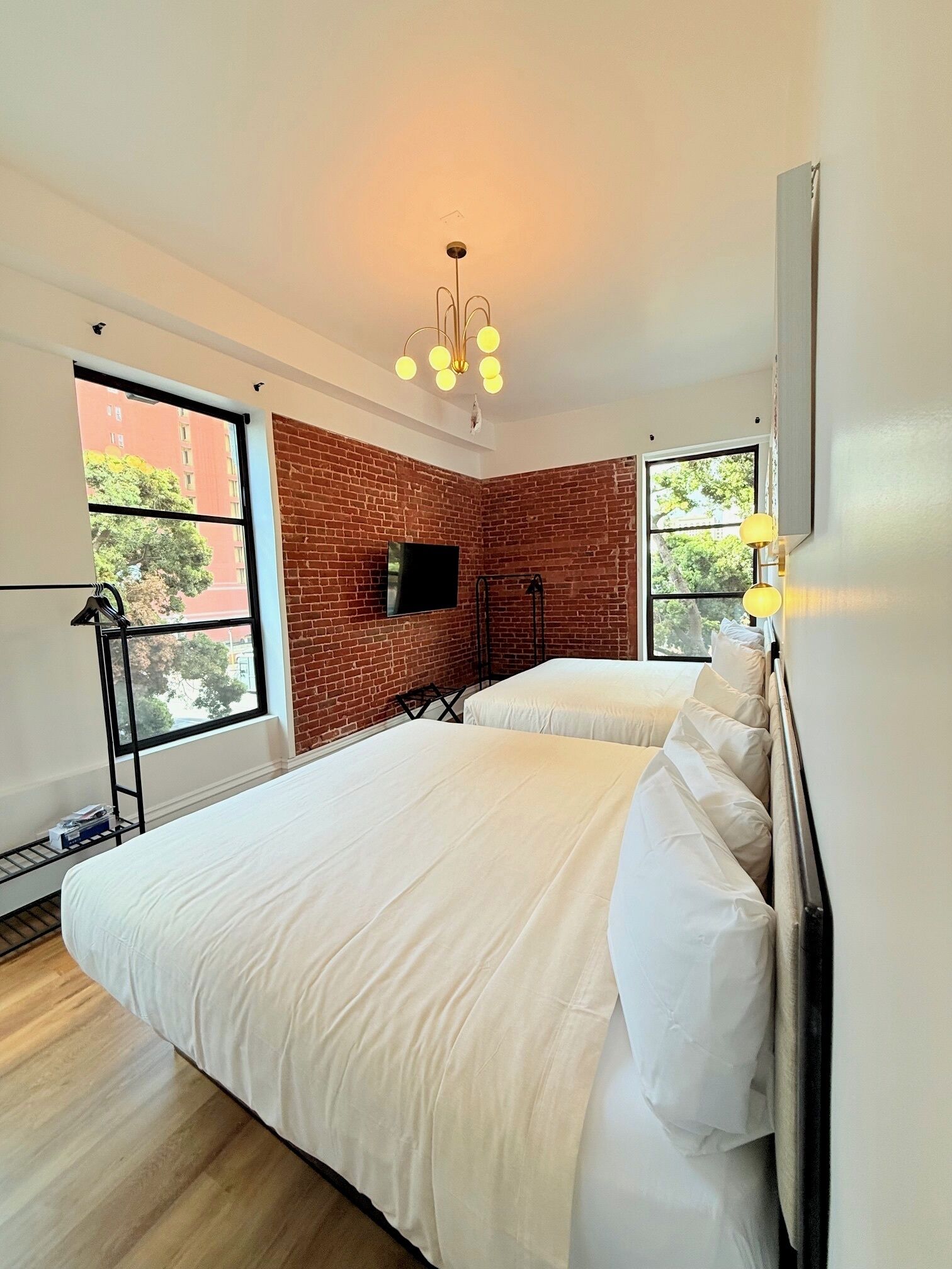 Une chambre avec deux lits, une télévision et un mur en briques.