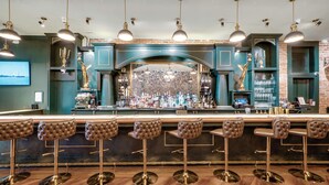 A bar area with a marble backsplash, green bar stools, and overhead lighting. - The Beau Hotel Gaslamp Quarter San Diego (San Diego)