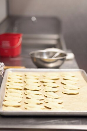 A tray of uncooked dumplings arranged on a baking sheet. - The Beau Hotel Gaslamp Quarter San Diego (San Diego)