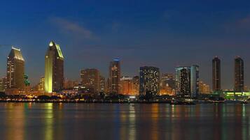 A nighttime city skyline with illuminated buildings reflecting on the water.