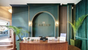 A reception desk with a sign reading "THE BEAU" and a sign indicating hotel amenities. - The Beau Hotel Gaslamp Quarter San Diego (San Diego)