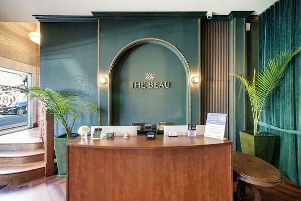 A reception desk with a sign reading "THE BEAU" and a sign indicating hotel amenities. - The Beau Hotel Gaslamp Quarter San Diego (San Diego)