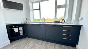 Una cucina moderna con mobili scuri, forno integrato e finestra vista all'esterno.
