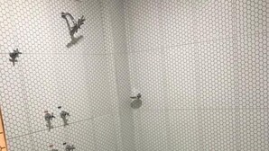Un baño con pared de azulejos hexagonales, una bañera grande y una ducha con un solo grifo.