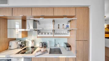 A modern kitchen with wooden cabinets, a built-in oven, a coffee machine, and a toaster.