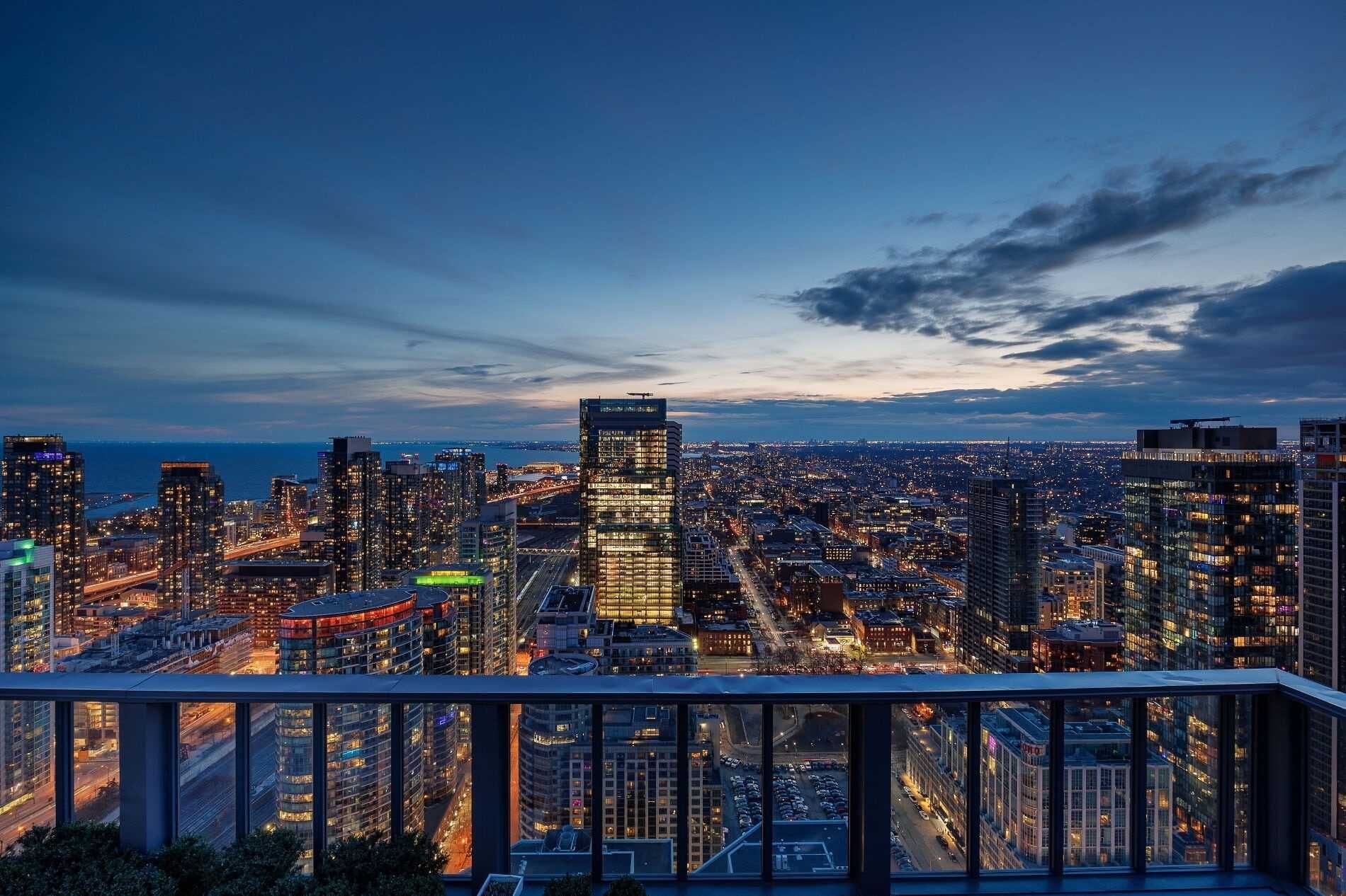 A cityscape at dusk with high-rise buildings, a view of the water, and a clear sky.