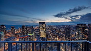 A cityscape at dusk with high-rise buildings, a view of the water, and a clear sky.