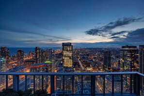 A cityscape at dusk with high-rise buildings, a view of the water, and a clear sky.