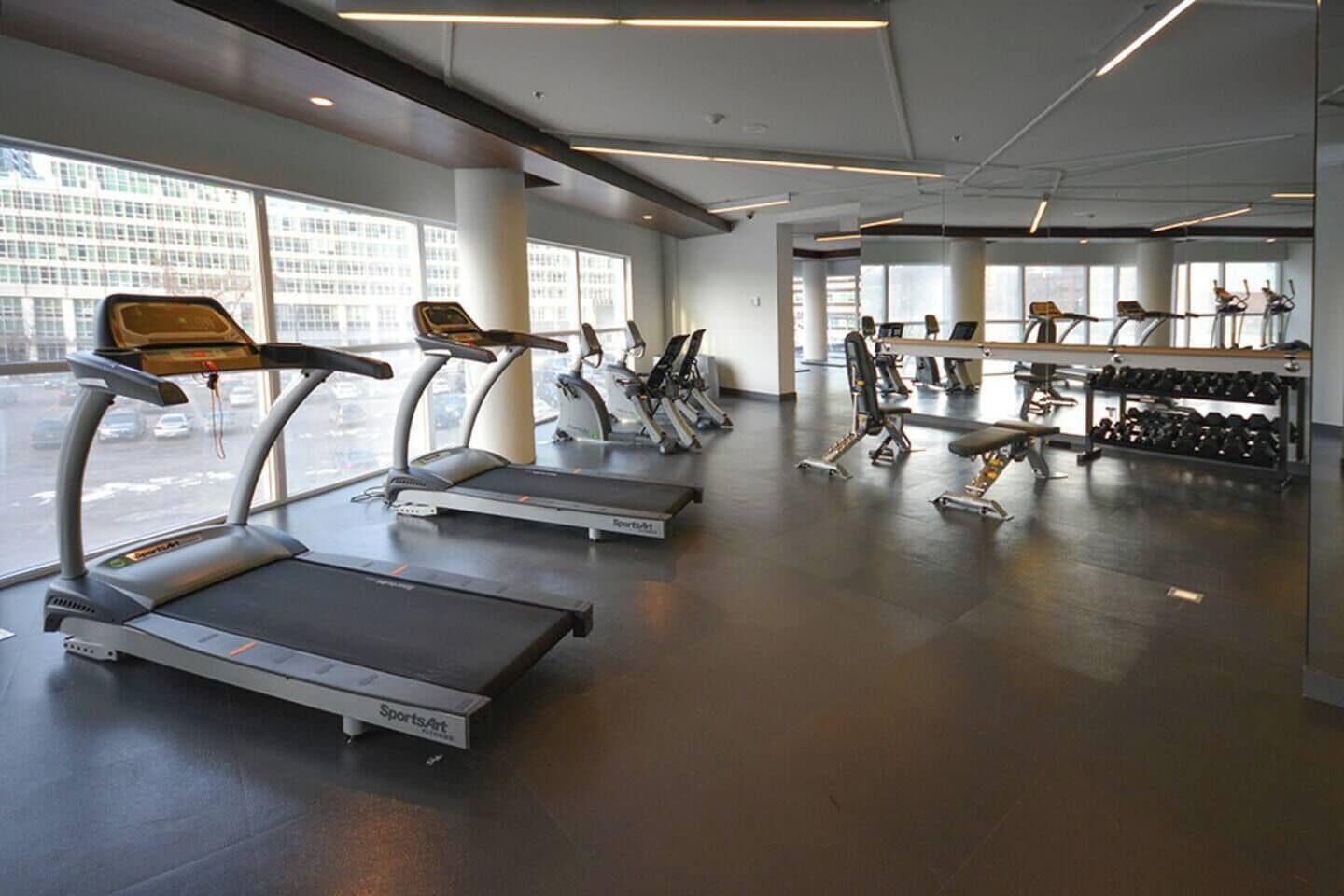 Un gimnasio con cintas de correr, elípticas y bancos de pesas.