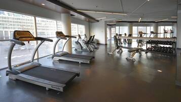 Un gimnasio con cintas de correr, elípticas y bancos de pesas.