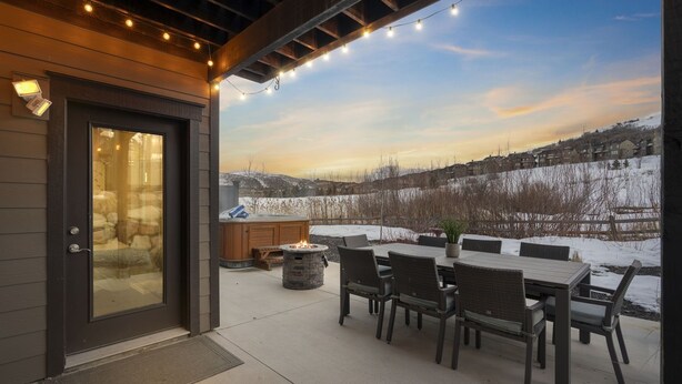 A patio with a fire pit, outdoor seating, and a view of a snowy landscape.