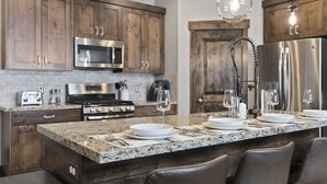 A modern kitchen with granite countertops, stainless steel appliances, and wooden cabinets.