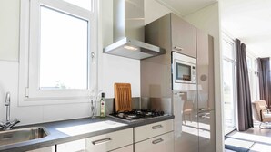A modern kitchen with a gas stove, a microwave, and a stainless steel range hood.