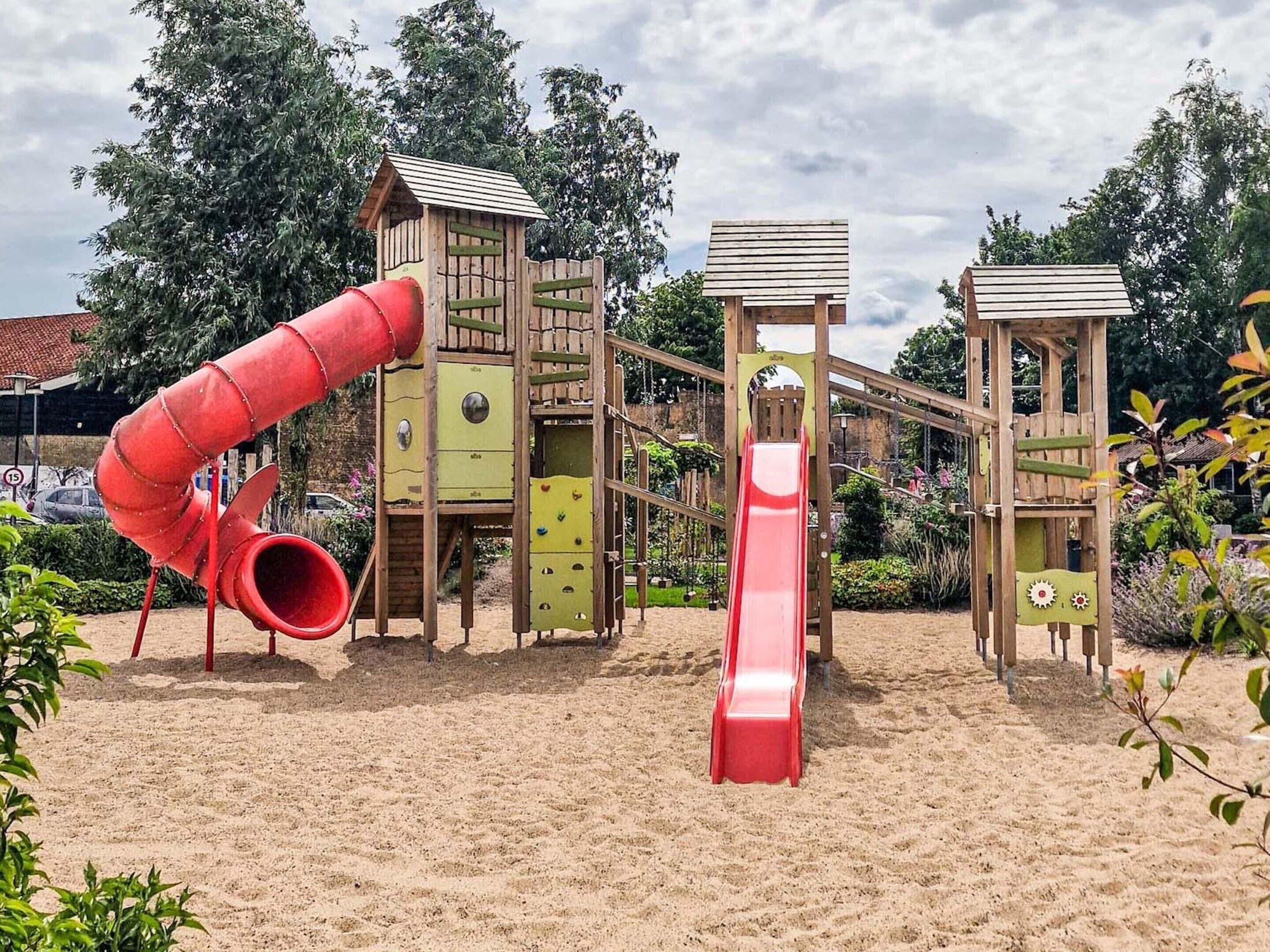 A playground with a red slide and a climbing structure.