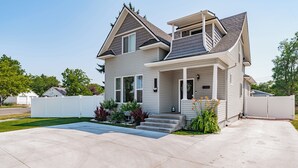 A two-story house with a front porch, a covered entryway, and a driveway. - Pet Friendly Downtown Vintage House w/ Hot Tub! (Idaho Falls)