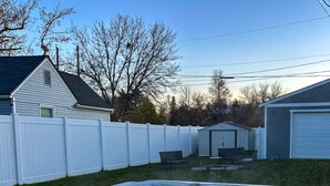 A hot tub in a backyard with a white fence, a small shed, and leafless trees. - Pet Friendly Downtown Vintage House w/ Hot Tub! (Idaho Falls)
